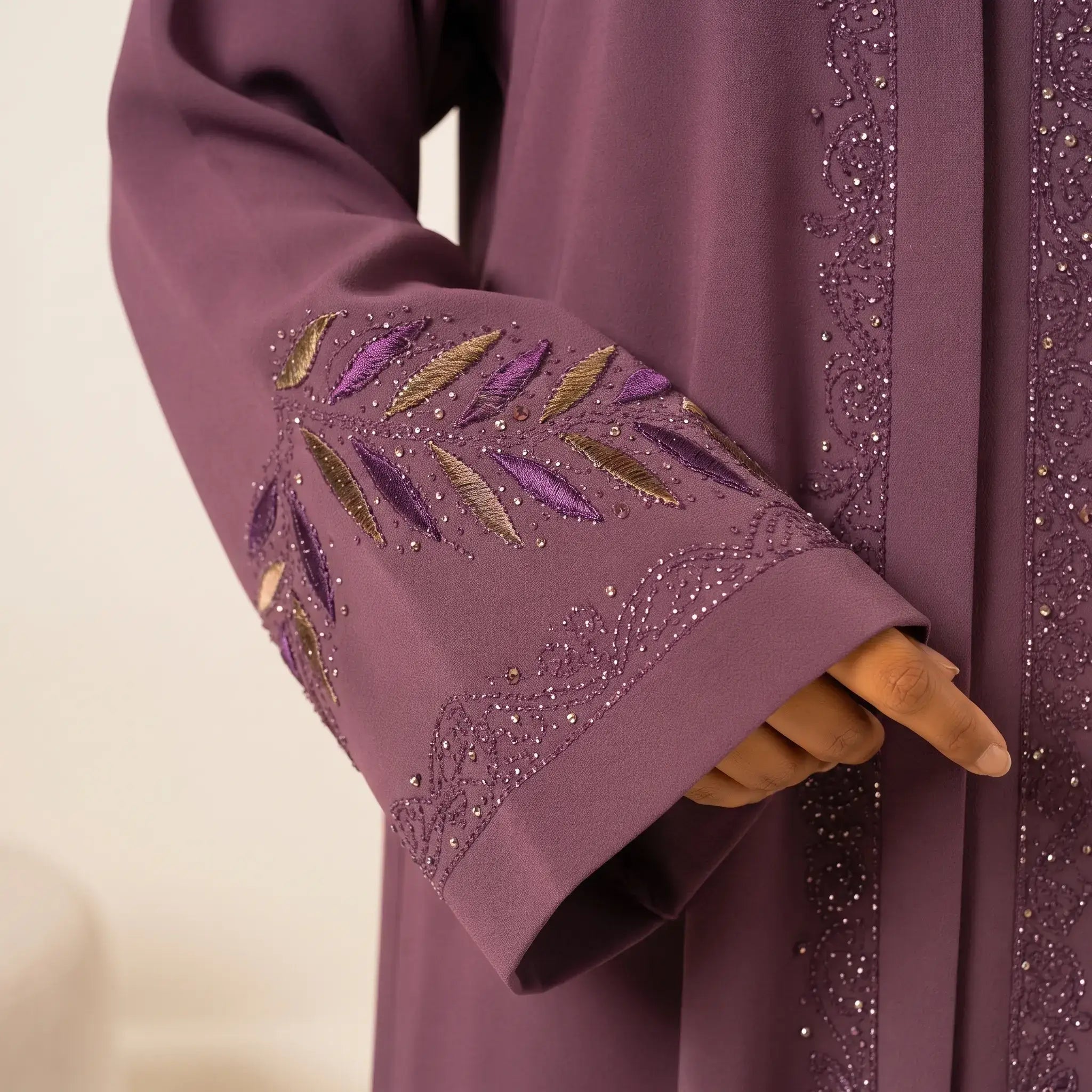 Close-up of multi-colour embroidered leaf and feather branch cuff with crystal beading on dusty mauve abaya
